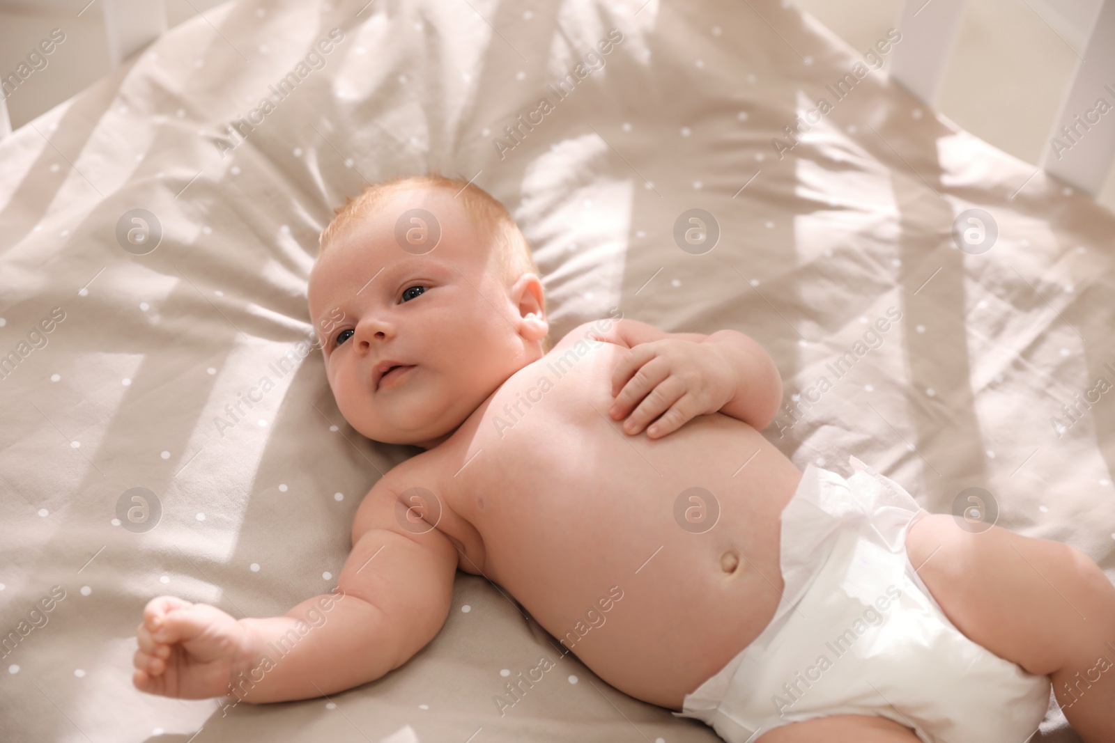 Photo of Cute healthy baby lying in cot, view from above.