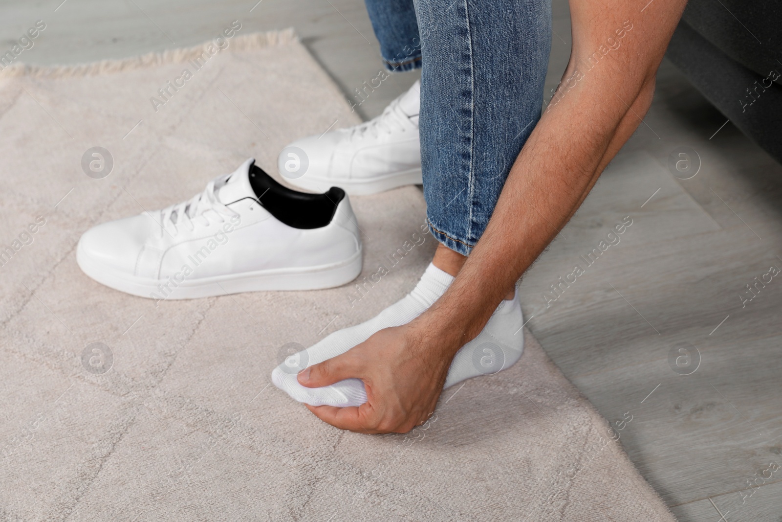 Photo of Man suffering from foot pain at home, closeup