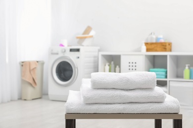 Stack of clean towels on table in bathroom.  Space for text