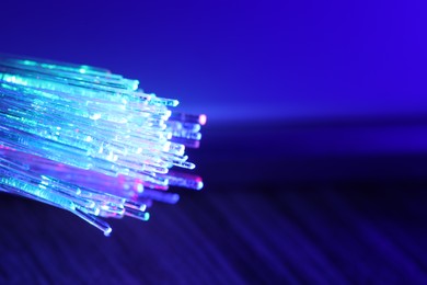 Optical fiber strands transmitting different color lights against blurred background, macro view. Space for text