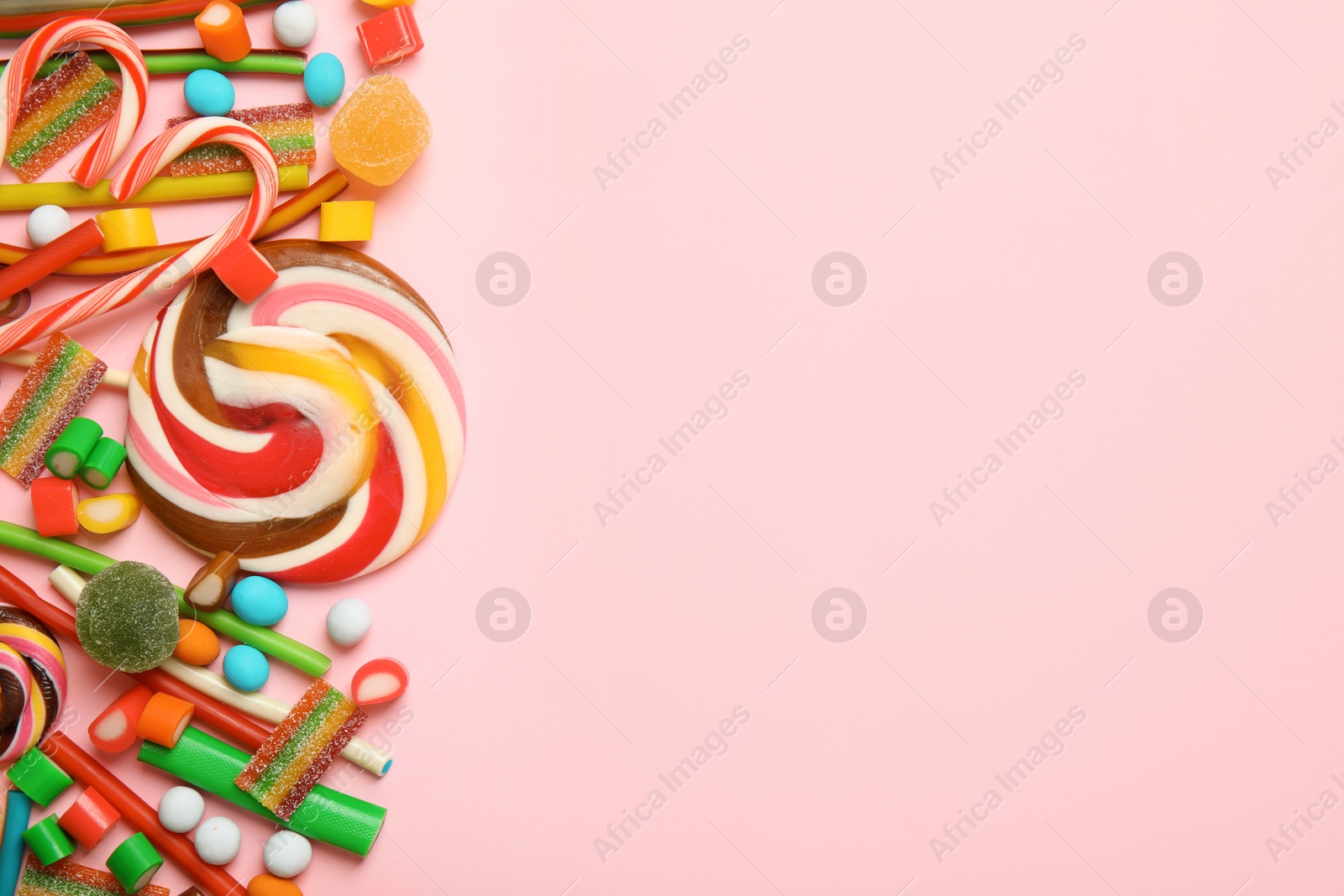 Photo of Flat lay composition with different yummy candies and space for text on color background