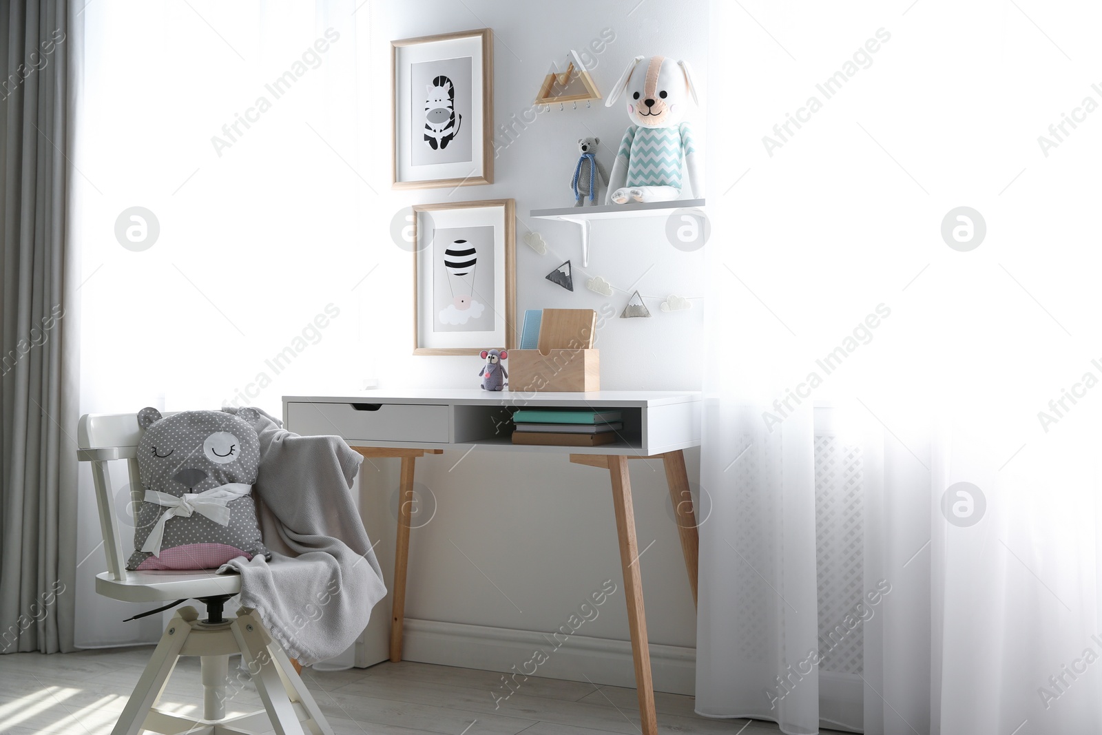 Photo of Stylish child's room interior with desk and beautiful pictures