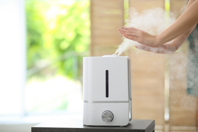 Woman near air humidifier indoors, closeup. Space for text