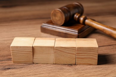Photo of Law. Blank wooden cubes and gavel on table, closeup