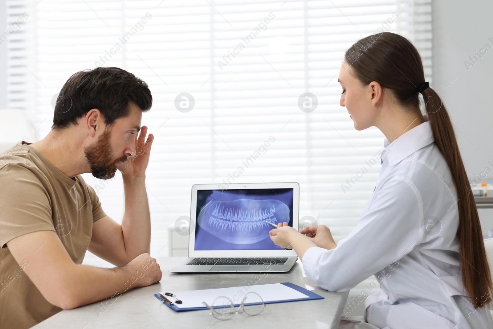 Photo of Dentist consulting patient before implants installation in clinic