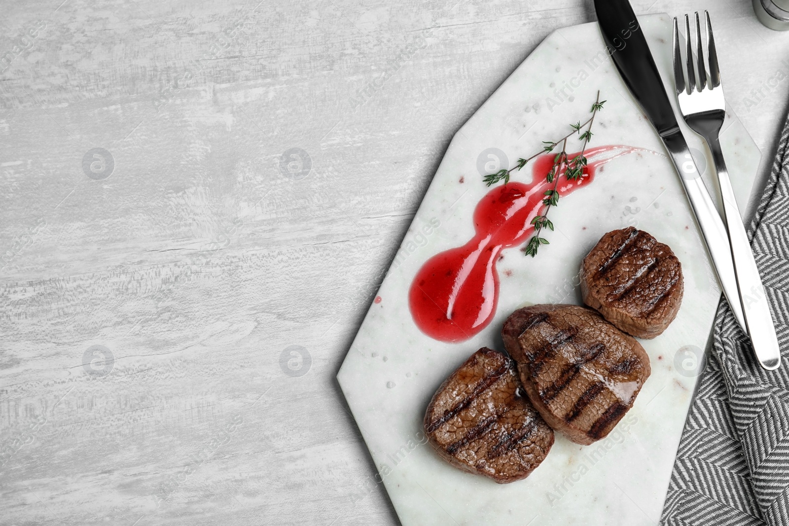 Photo of Stone board with grilled meat and sauce on light background, top view. Space for text