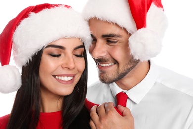 Photo of Lovely young couple in Santa hats on white background, closeup. Christmas celebration