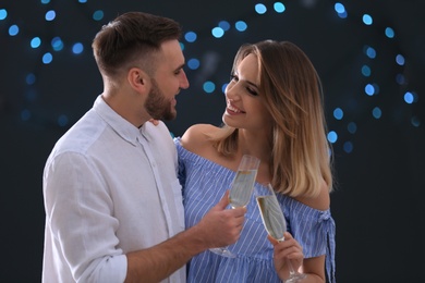 Photo of Happy couple with champagne in glasses on blurred background