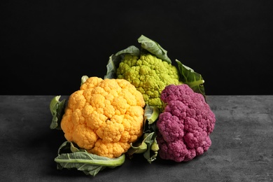 Photo of Colorful cauliflower cabbages on table against black background. Healthy food