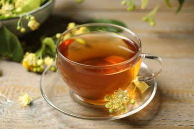 Photo of Cup of tea and linden blossom on wooden table