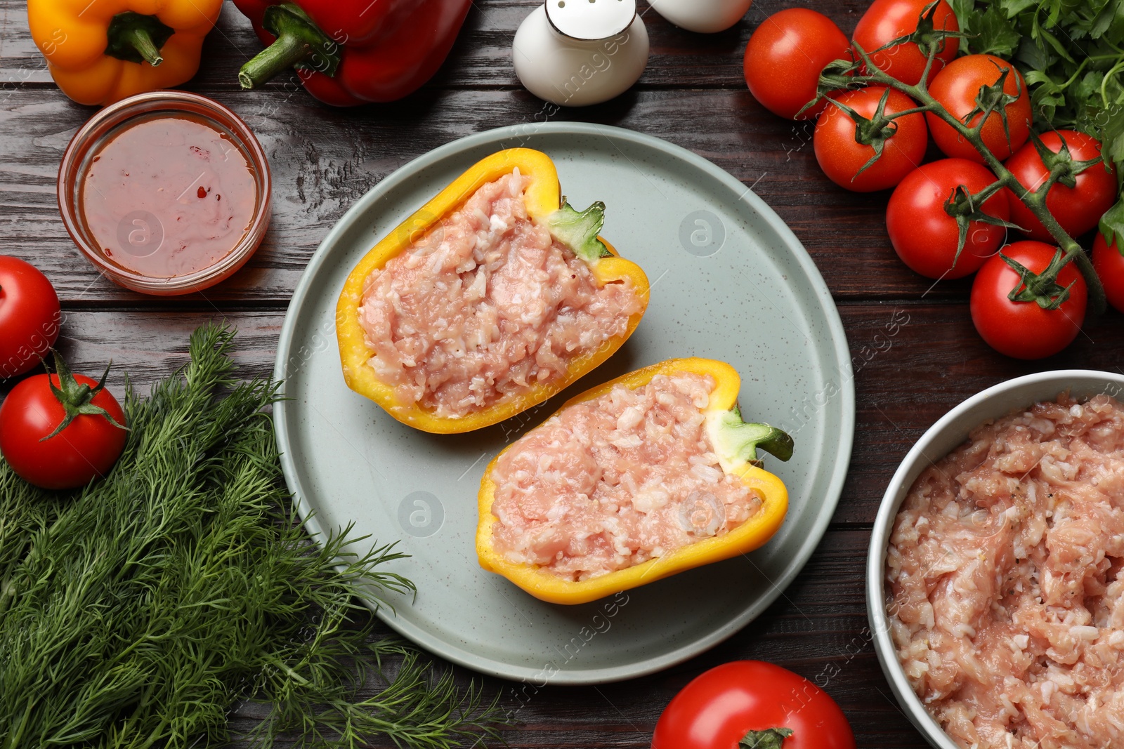 Photo of Raw stuffed peppers with ground meat and ingredients on wooden table, flat lay