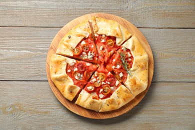 Photo of Tasty galette with tomato, rosemary and cheese (Caprese galette) on wooden table, top view