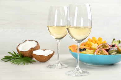 Delicious exotic fruits and wine on white wooden table