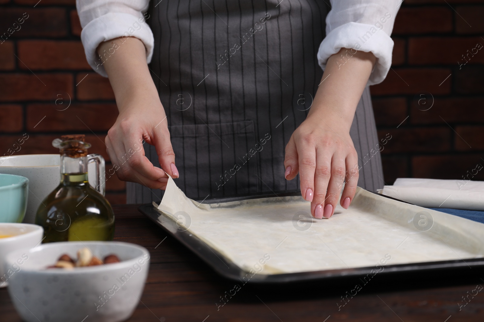 Photo of Woman making delicious baklava at wooden table, closeup