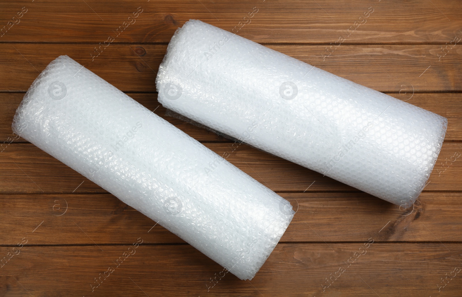 Photo of Bubble wrap rolls on wooden background, flat lay