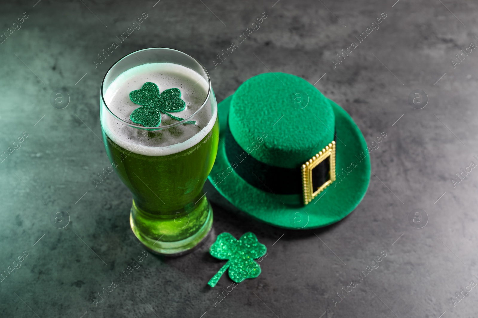 Photo of St. Patrick's day celebration. Green beer, leprechaun hat and decorative clover leaves on grey table