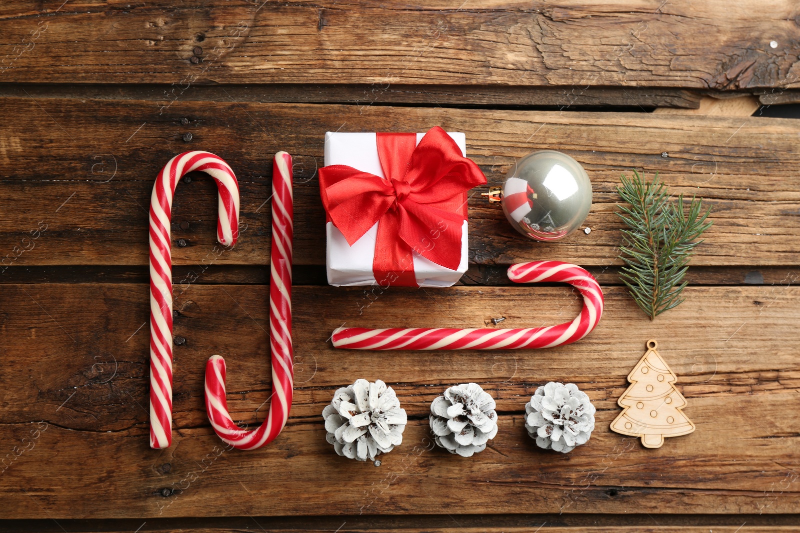 Photo of Flat lay composition with candy canes and Christmas decor on wooden background