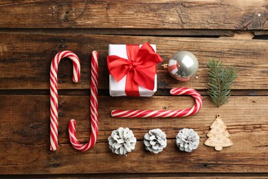 Photo of Flat lay composition with candy canes and Christmas decor on wooden background