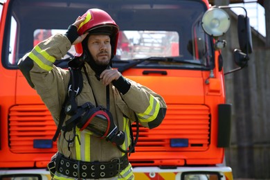 Portrait of firefighter in uniform near fire truck outdoors