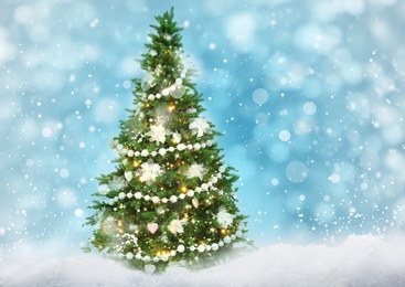 Image of Beautiful decorated Christmas tree on light blue background. Bokeh effect