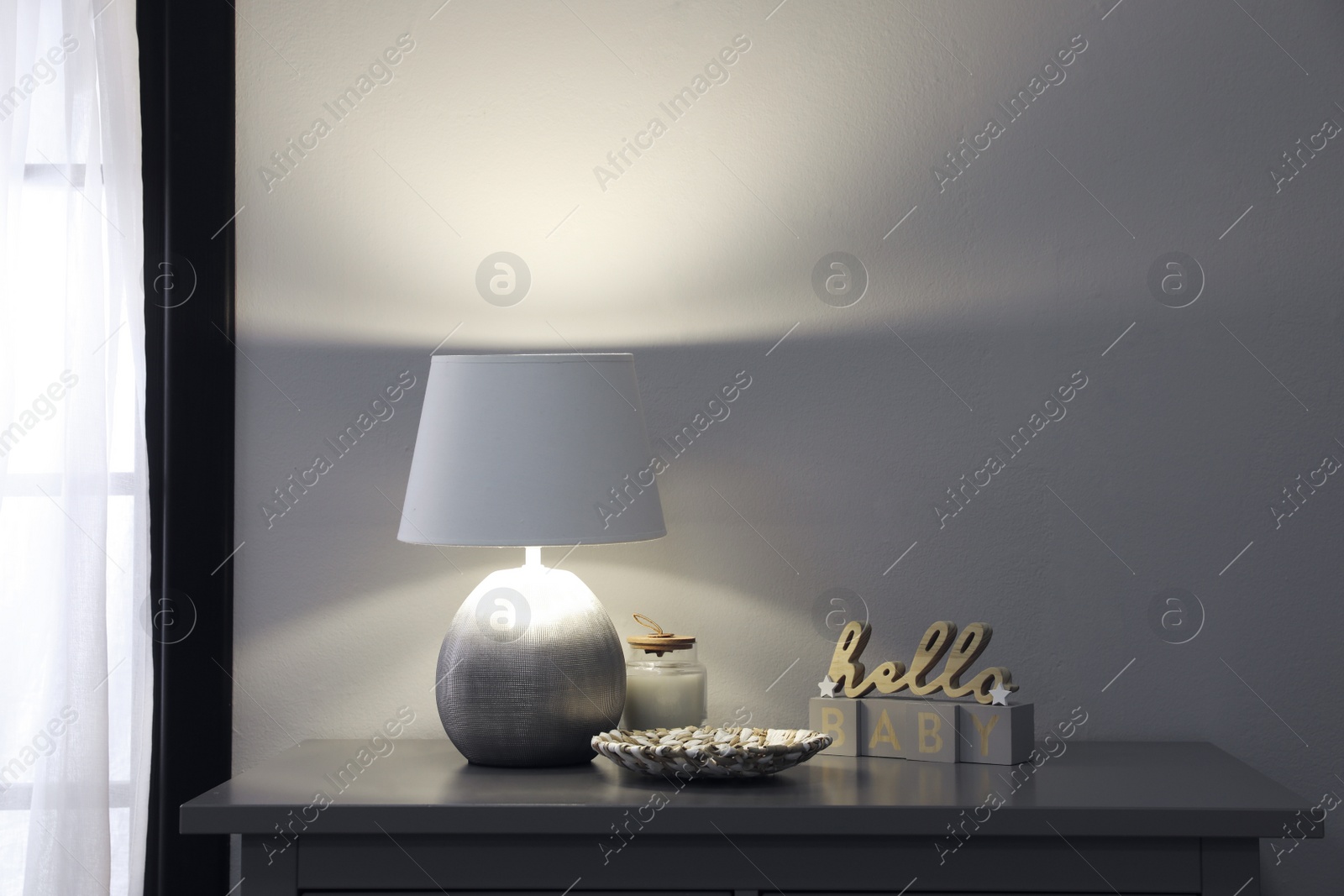 Photo of Stylish lamp and decor on grey table indoors. Interior design