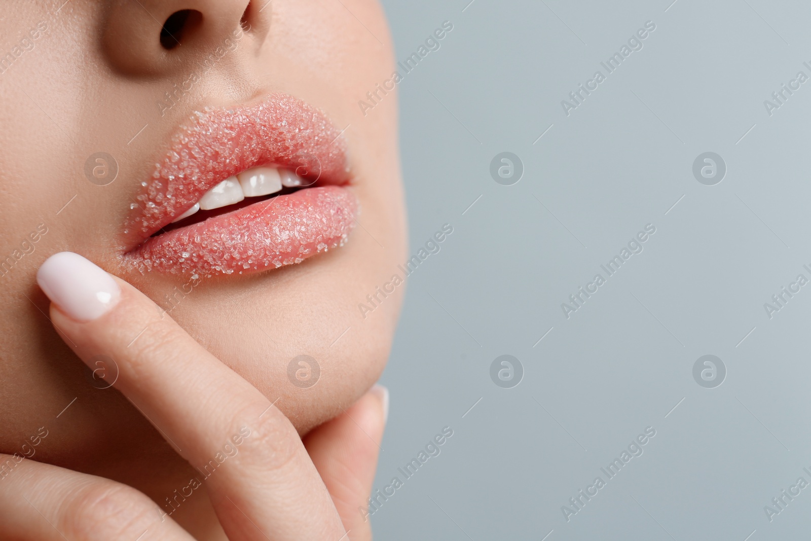 Photo of Closeup view of woman with lips covered in sugar on light grey background. Space for text