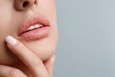 Closeup view of woman with lips covered in sugar on light grey background. Space for text