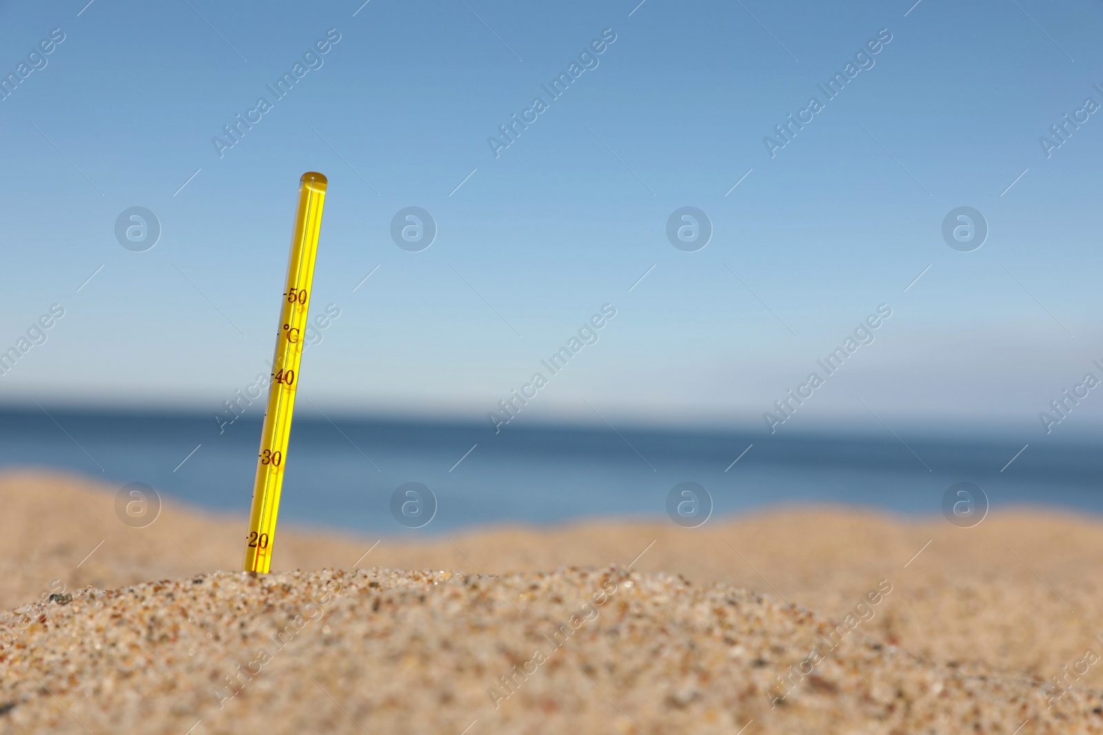 Photo of Weather thermometer in sand near sea, space for text
