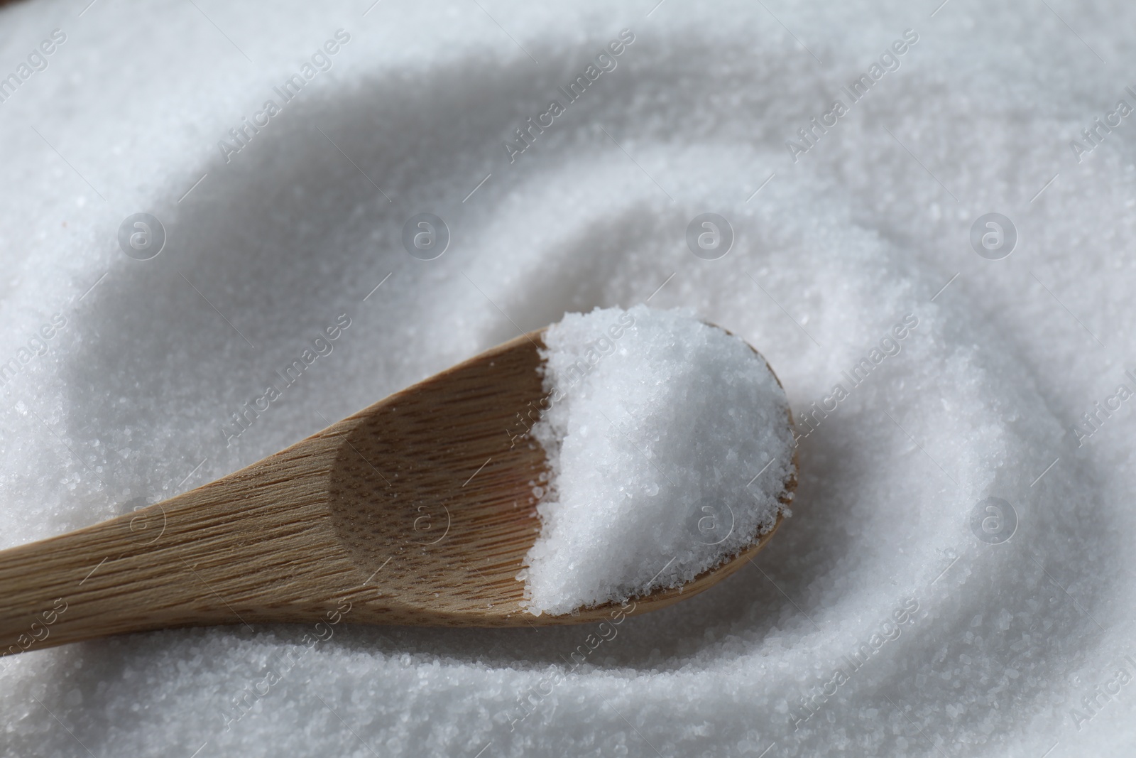 Photo of Wooden spoon on white sea salt, closeup