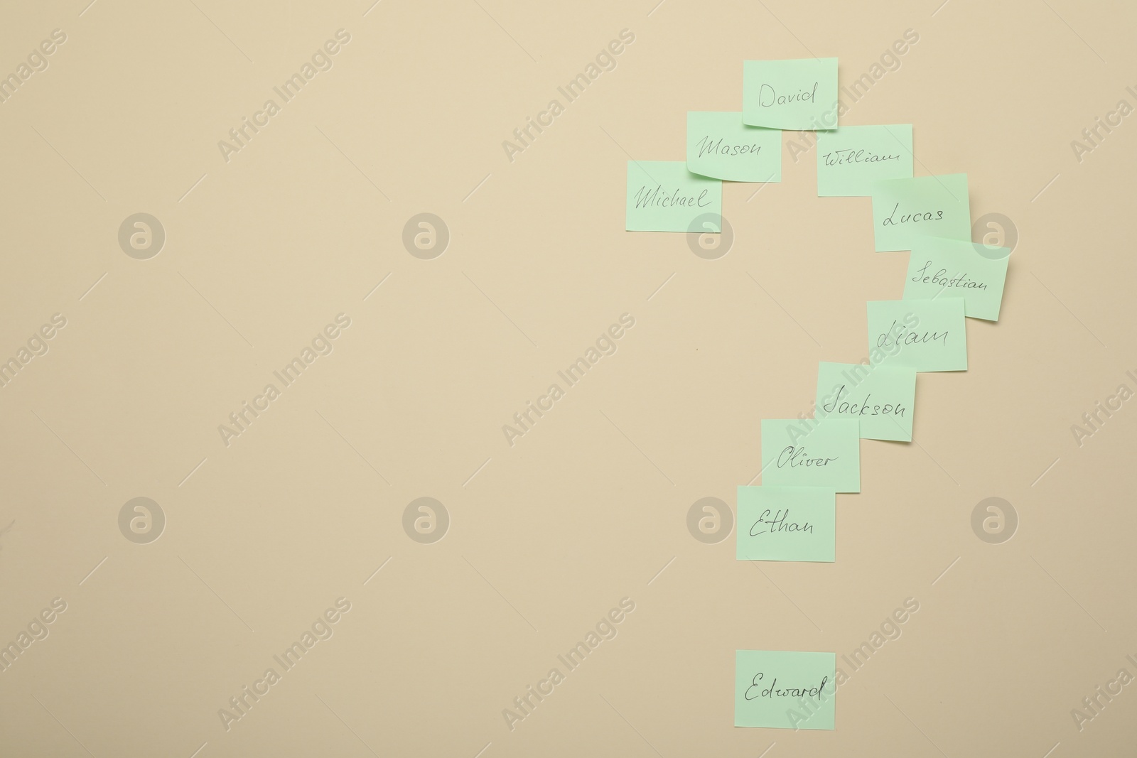 Photo of Choosing baby`s name. Paper stickers with different names in shape of question mark on beige background, top view. Space for text