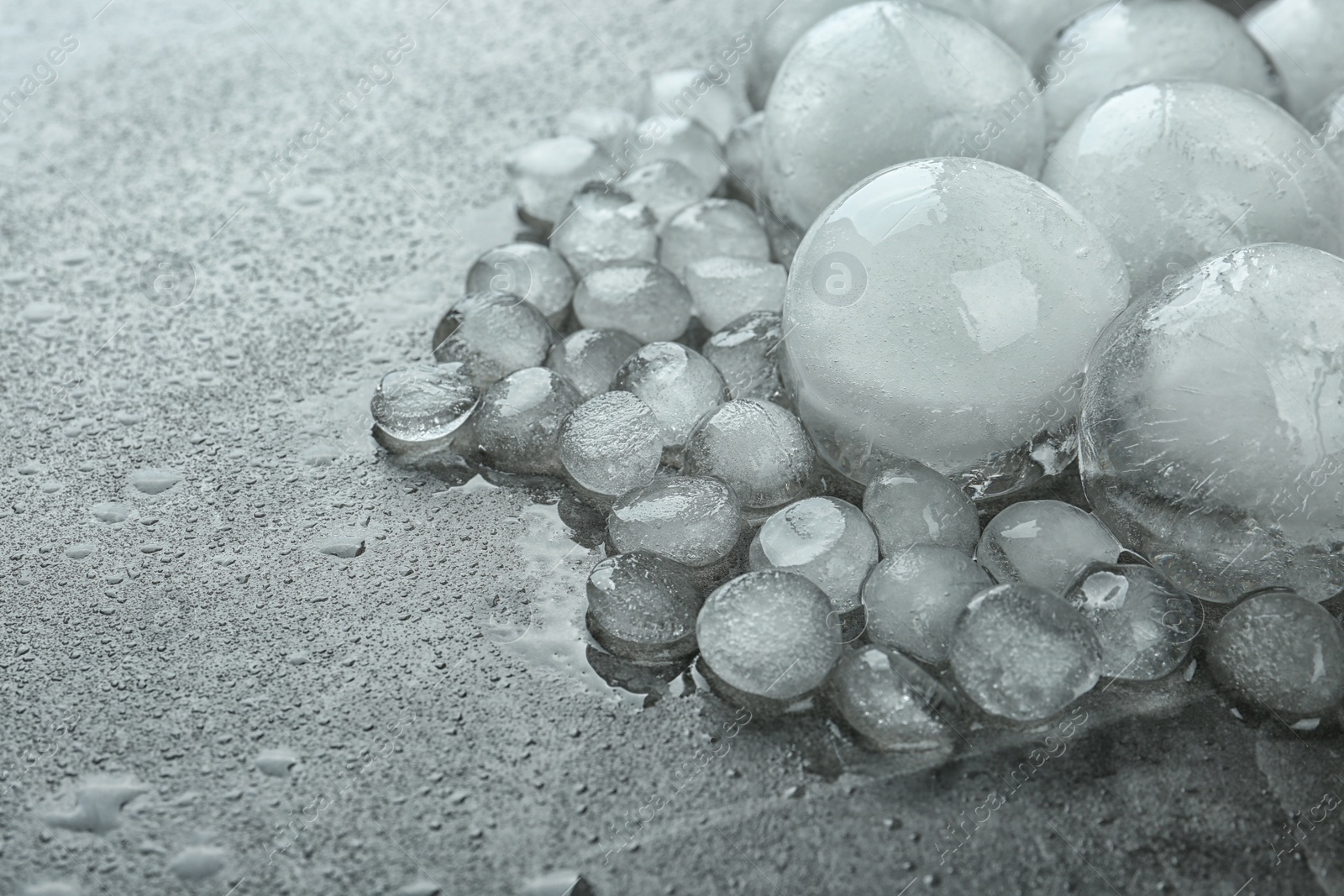 Photo of Many melting ice balls on dark grey table, closeup. Space for text