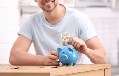 Man with piggy bank and money at home, closeup