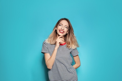 Beautiful young woman with healthy long blonde hair on color background