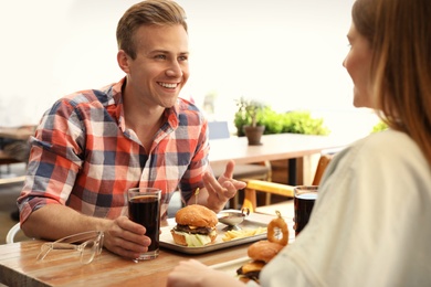 Photo of Young happy couple with burgers in street cafe