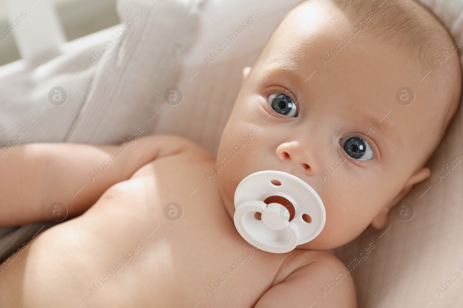 Photo of Cute little baby with pacifier lying in crib