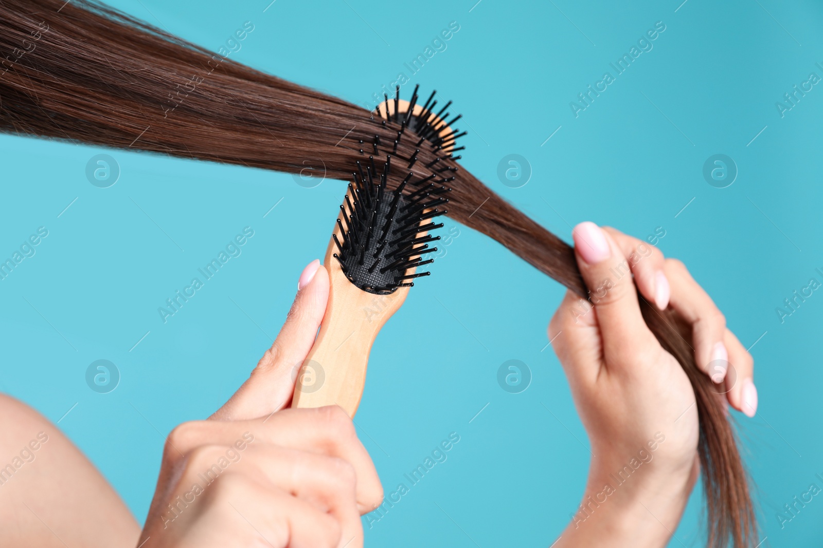 Photo of Woman with hair brush on color background, closeup