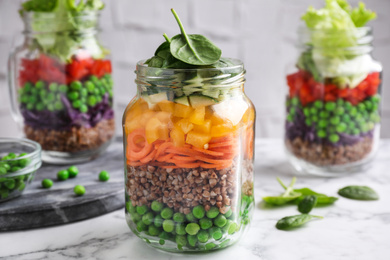 Photo of Healthy salads in glass jars on marble table