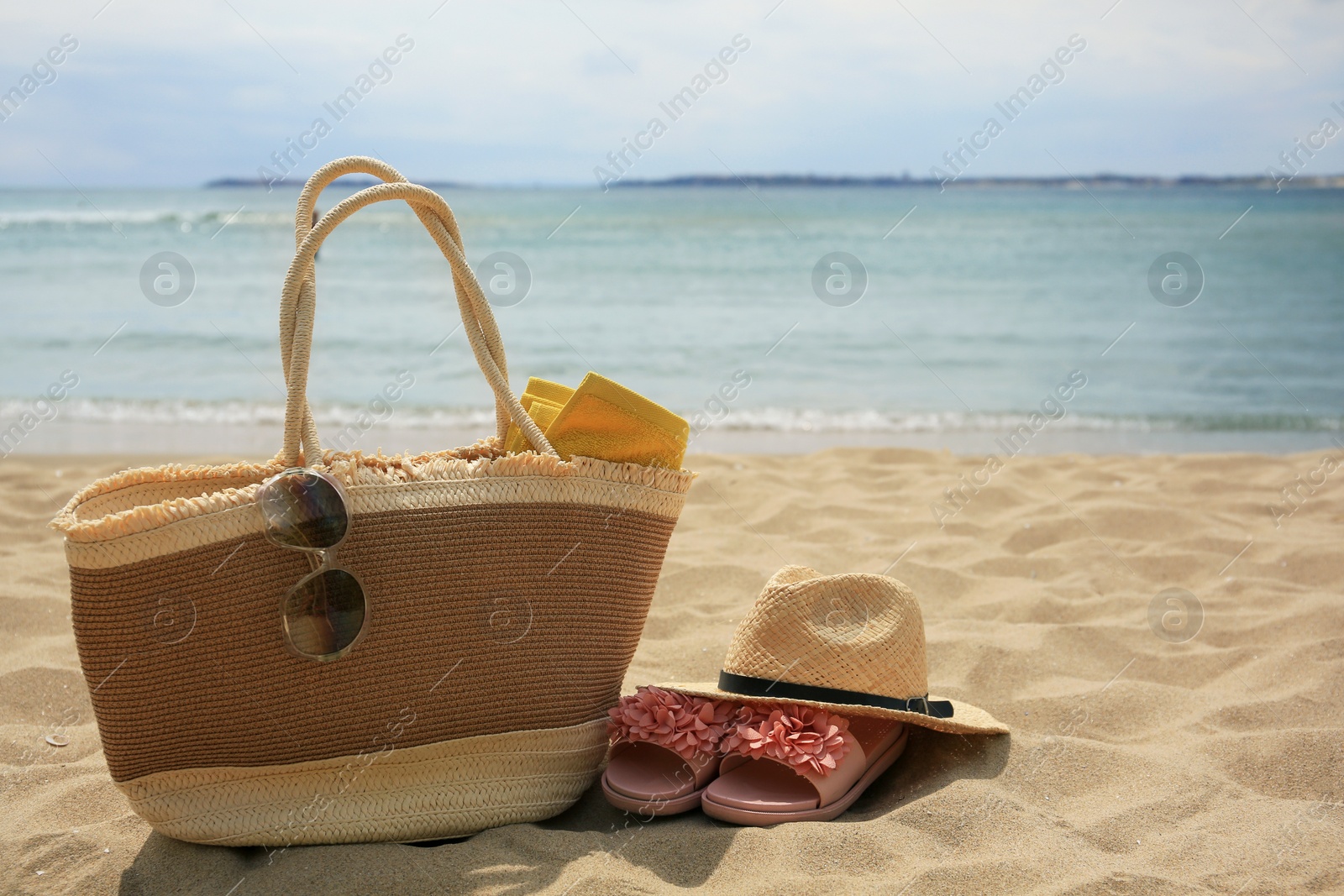 Photo of Bag, slippers and other beach items on sandy seashore. Space for text