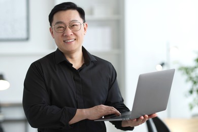 Portrait of smiling businessman with laptop in office