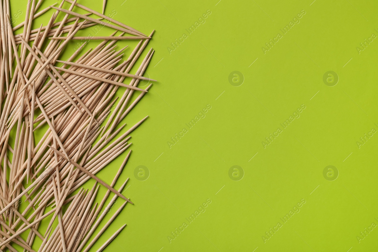 Photo of Wooden toothpicks on green background, flat lay. Space for text