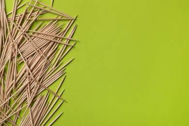 Photo of Wooden toothpicks on green background, flat lay. Space for text