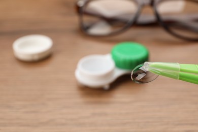 Tweezers with contact lens over table, closeup. Space for text