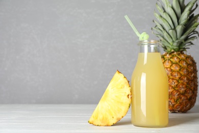 Photo of Delicious pineapple juice and fresh fruit on white wooden table. Space for text