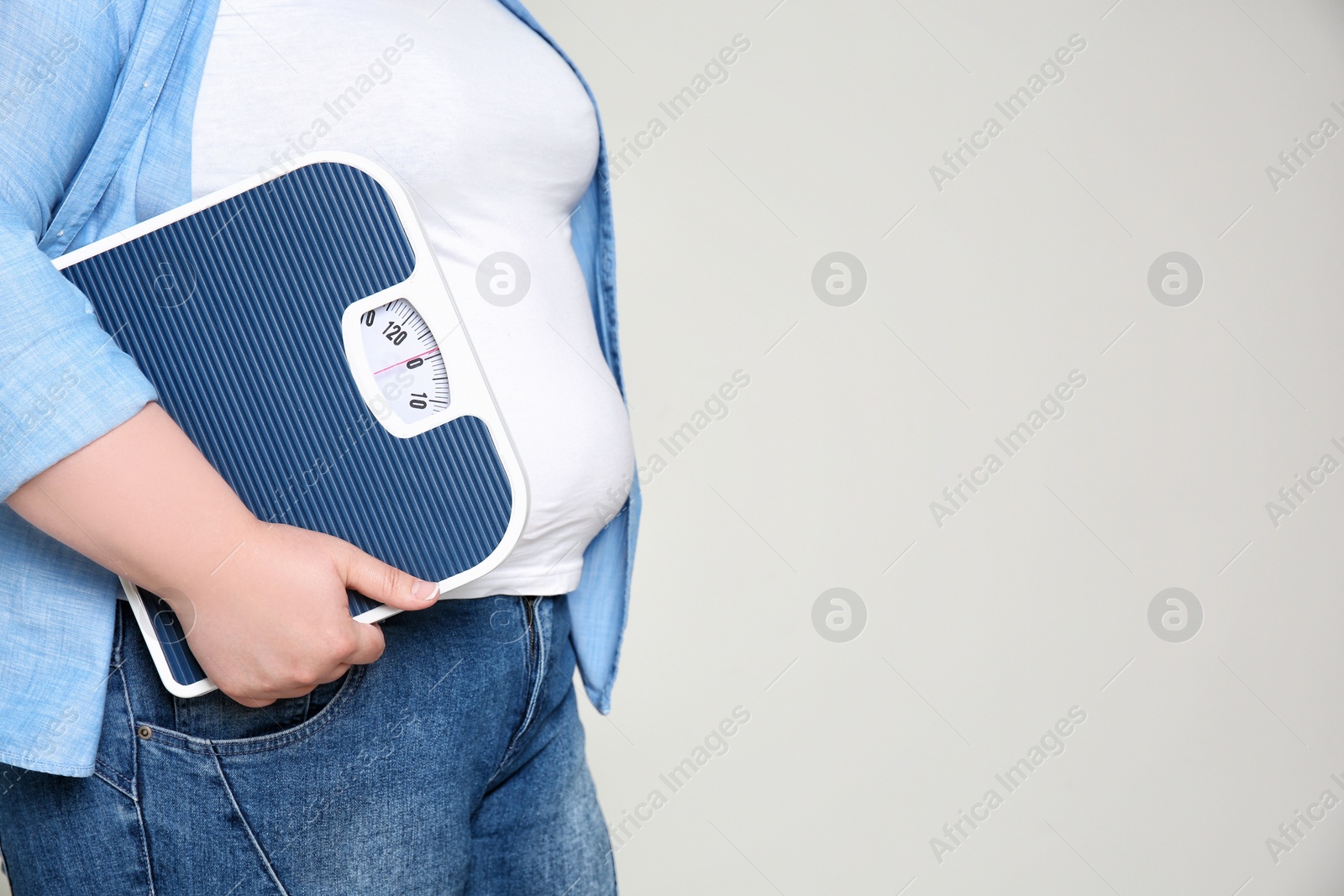 Photo of Overweight woman with scales on light background