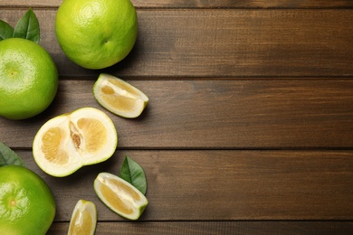 Whole and cut sweetie fruits on wooden table, flat lay. Space for text