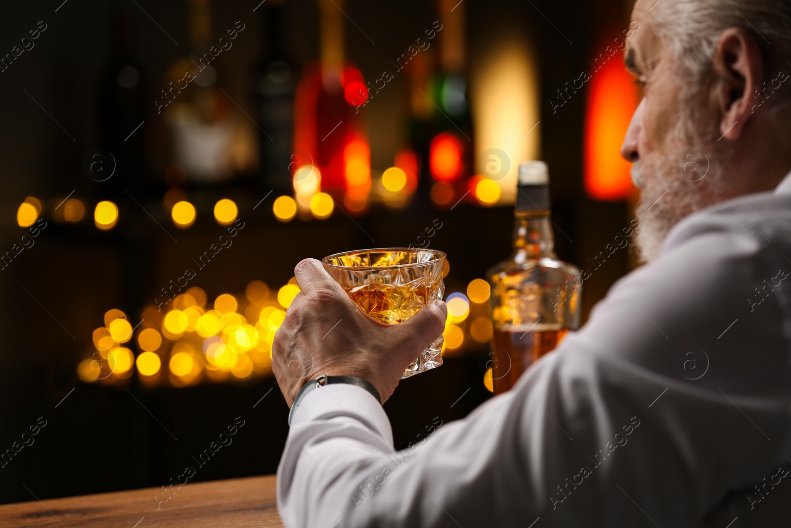 Photo of Senior man with glass of whiskey at bar counter, closeup. Space for text