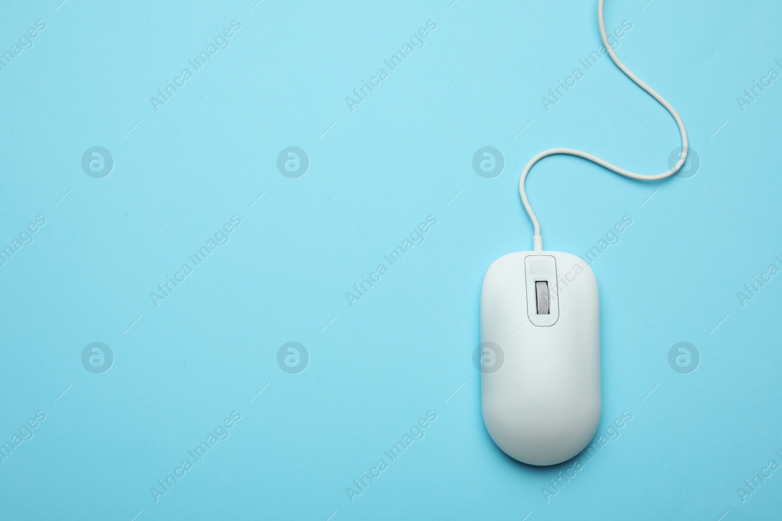 Photo of Wired computer mouse on light blue background, top view. Space for text