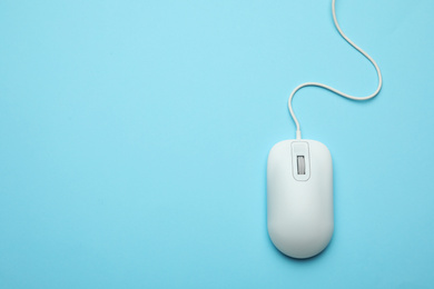 Photo of Wired computer mouse on light blue background, top view. Space for text