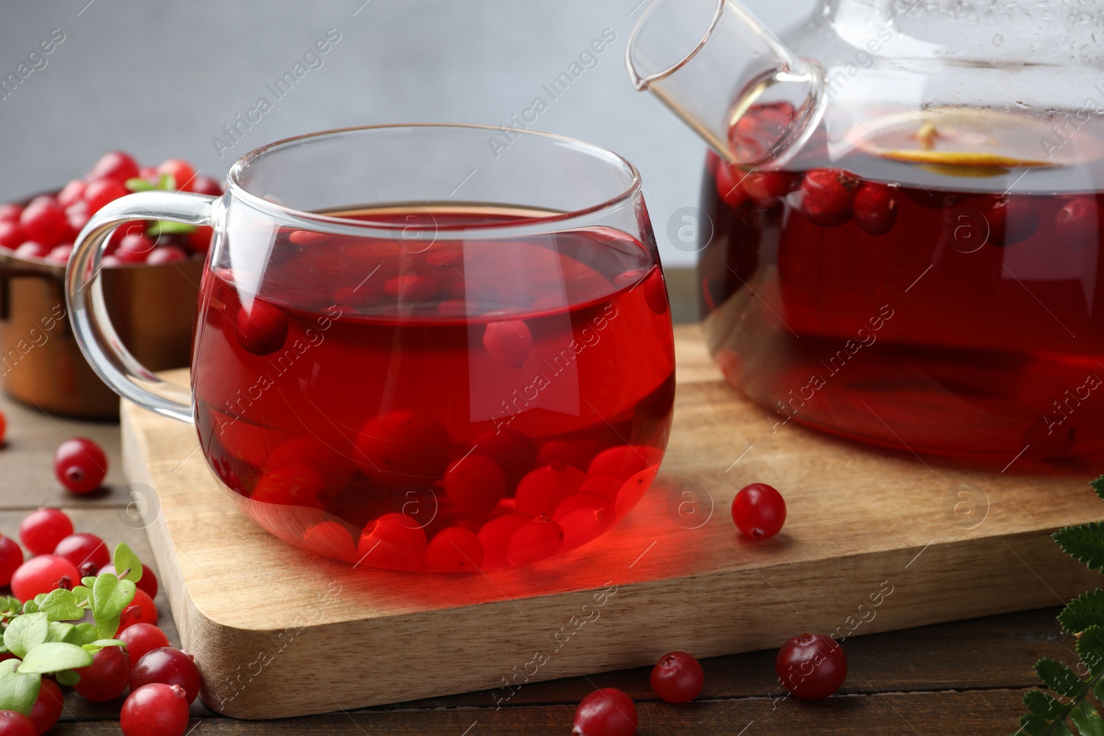 Photo of Tasty hot cranberry tea and fresh berries on wooden table