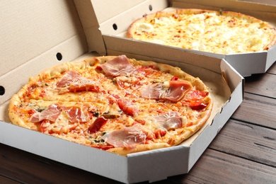 Photo of Carton boxes with delicious pizzas on wooden background